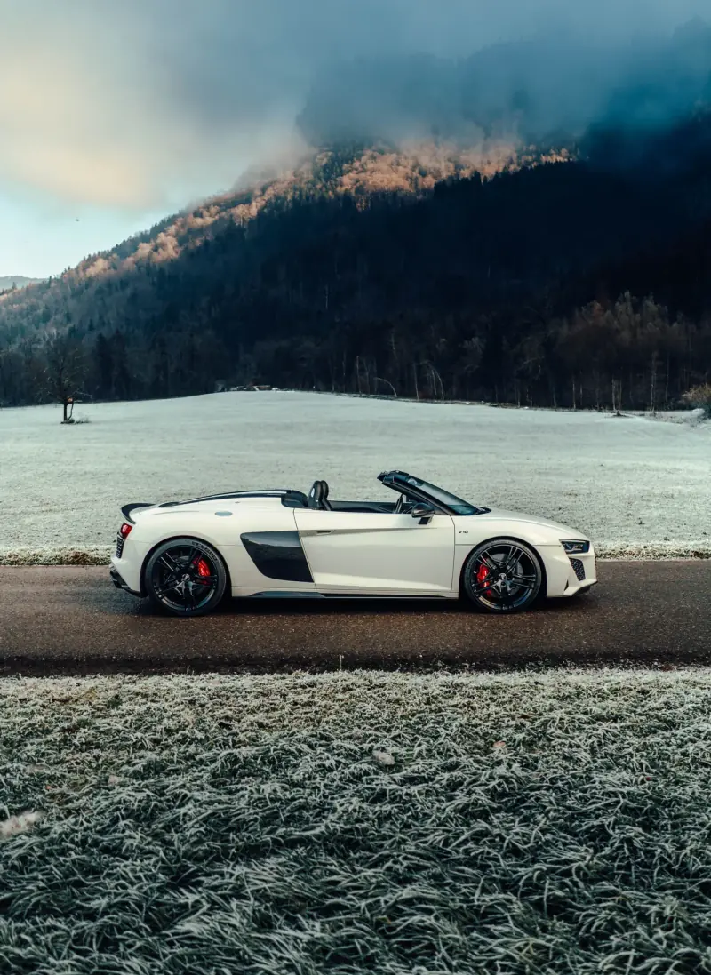 Audi R8 Spyder su una strada coperta di brina davanti a una parete rocciosa